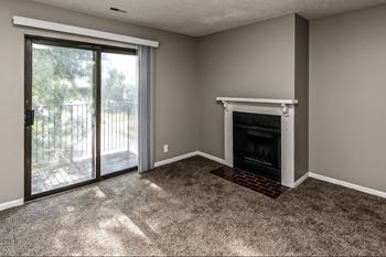 an empty living room with a fireplace and a patio door